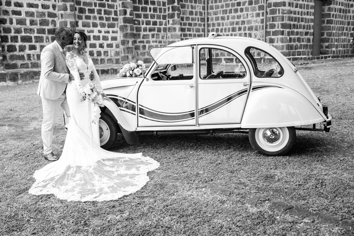 Photographie noir et blanc : la longue traîne de la robe déployée devant la 2CV