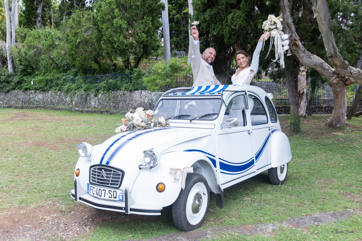 Emma et Fabien debout dans le toit ouvert de la 2CV, bras levés