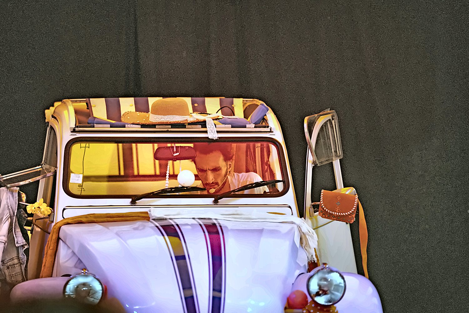 Artiste au volant de la 2CV de collection, chapeau rouge, en scène